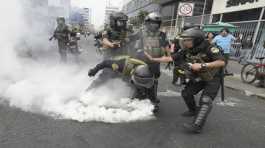 Police officers pick up a tear gas canister