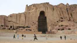 Young people play football in front of the Buddha site