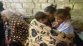 Children eat sitting in a shelter during shelling